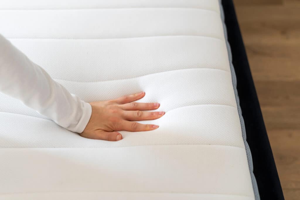 Hand pressing into latex mattress showing bounce and responsiveness